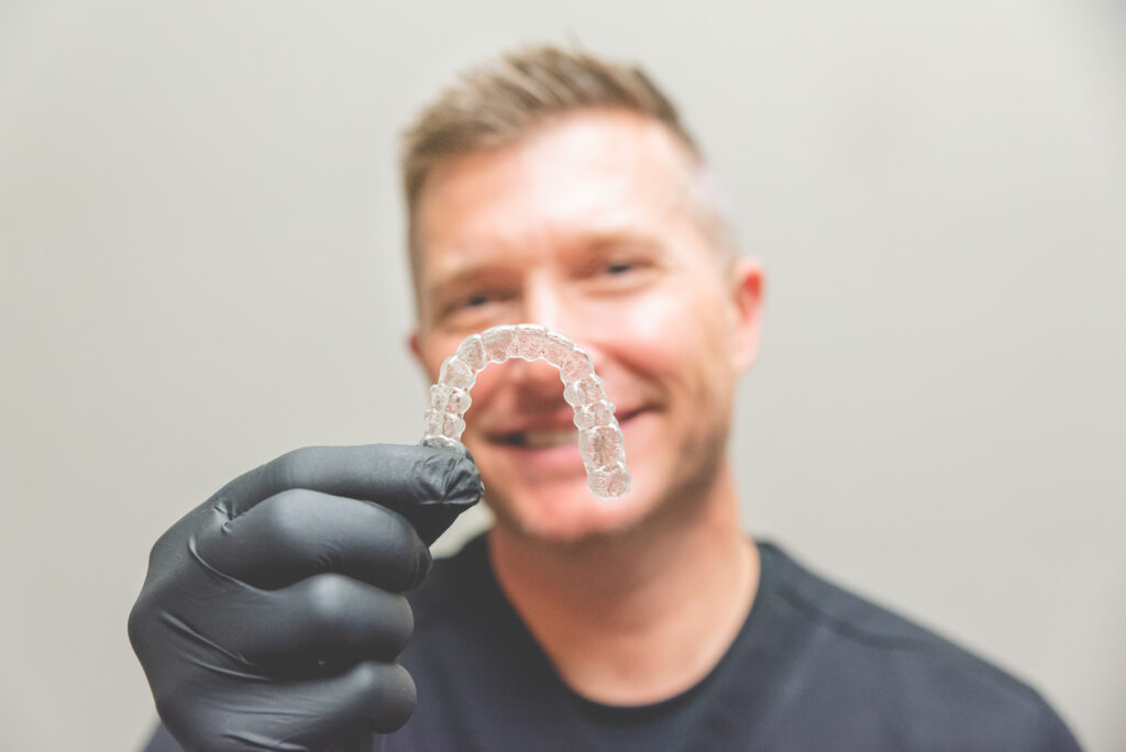 Our Frisco dentist, dr. Belman, holding Invisalign.